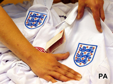 A UK Border Agency officer inspects a fake Umbro England shirt at East Midlands Airport